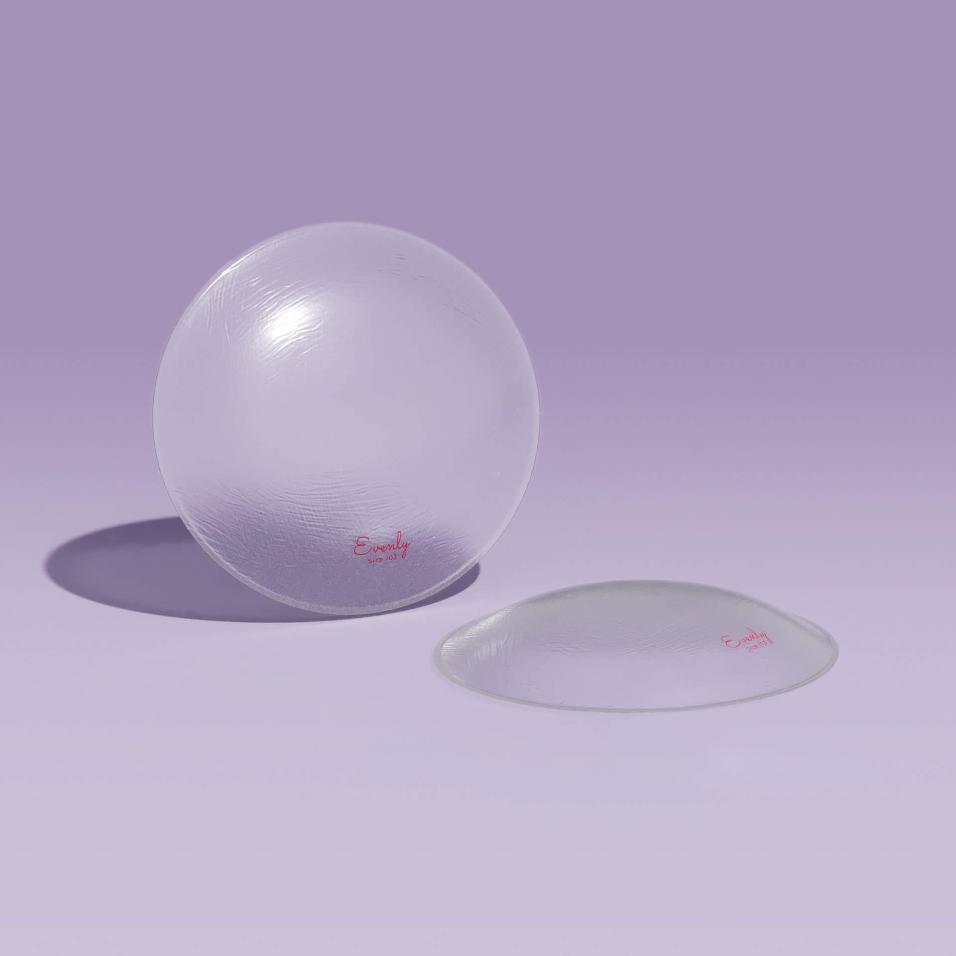 Two clear silicone bra balancers on a light purple background