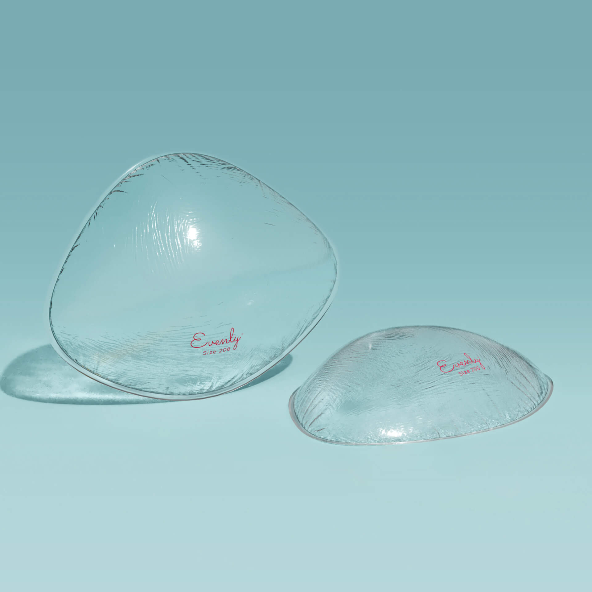 Two clear silicone breast inserts on a light blue background